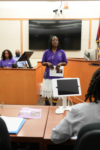 Pamela Neal standing in front of a group of students holding a paper.
