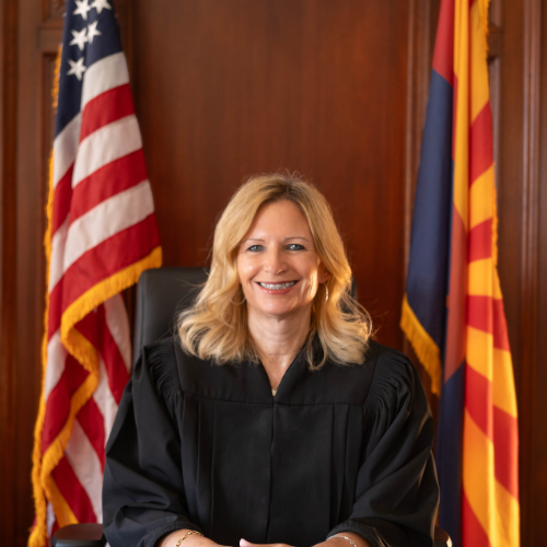 Judge Gates seated at the courtroom bench flanked by the United States flag and Arizona state flag.